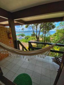 a hammock on a porch with a view of the ocean at Pousada Palmeiras in Bombinhas