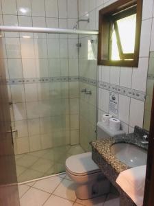 a bathroom with a shower and a toilet and a sink at Pousada Palmeiras in Bombinhas