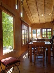 a dining room with a table and chairs and windows at Cabañas Puente Negro in Puente Negro