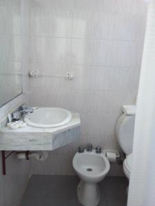 a white bathroom with a sink and a toilet at Hotel Escorial in Piriápolis