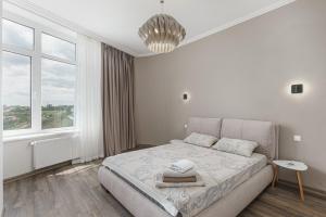 a white bedroom with a bed and a large window at Sea Symphony 2-bedrooms Apartment in Odesa
