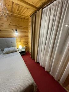 een slaapkamer met een bed en een raam met gordijnen bij Girske Povitria Cottage in Jaremtsje