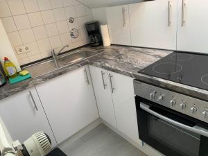 a kitchen with white cabinets and a sink and a stove at Gemütliche Ferienwohnung bei Hamburg in Reinbek