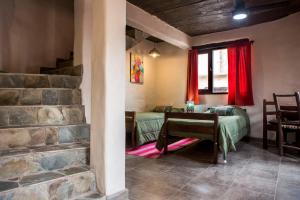a room with a stone wall and a bedroom with a table at Cabañas La Ekeka in Tilcara