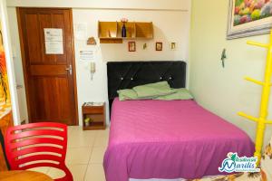 a bedroom with a pink bed and a red chair at Residencial Marilis in Palhoça
