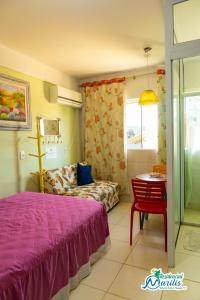a bedroom with a bed and a chair and a table at Residencial Marilis in Palhoça