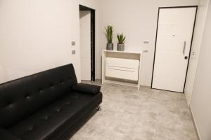 un soggiorno con divano nero in una camera di Trebbia House a Piacenza
