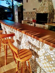 eine Bar mit zwei Stühlen und einer Holztheke in der Unterkunft Ganesh Chalés in Boracéia