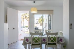 a white dining room with a table and chairs at Tranquilo apartamento. Piscina, playa y relax. in Sa Caleta