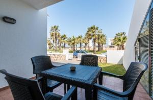 a table and chairs on a patio with a view of a yard at Tranquilo apartamento. Piscina, playa y relax. in Sa Caleta