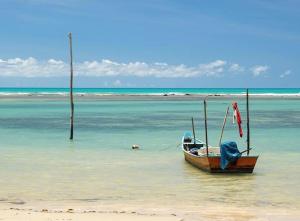 a boat sitting in the water on a beach at Paraíso Casa Branca in Arraial d'Ajuda +45 photos