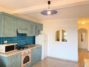a kitchen with blue cabinets and a white refrigerator at Casa Leo - Villaggio Baia De Bahas in Golfo Aranci