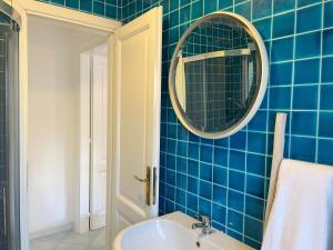 a blue tiled bathroom with a sink and a mirror at Casa Leo - Villaggio Baia De Bahas in Golfo Aranci