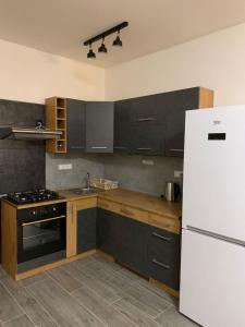 a kitchen with black cabinets and a white refrigerator at Apartmán na náměstí in Králíky