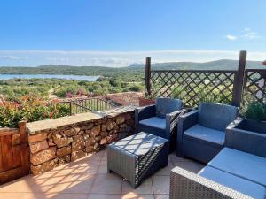 a patio with two chairs and a stone wall at Casa Leo - Villaggio Baia De Bahas in Golfo Aranci