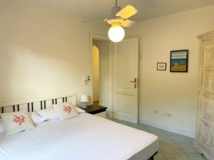a bedroom with a white bed and a ceiling fan at Casa Leo - Villaggio Baia De Bahas in Golfo Aranci
