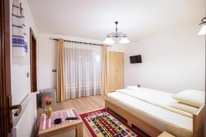 ein Schlafzimmer mit einem Bett und einem Tisch mit einem Teppich in der Unterkunft Casa Luca in Vişeu de Jos
