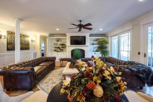 a living room with leather couches and a ceiling fan at New - Spectacular️ Golf Views - Sleeps 20 - Pinehurst National #9 - Near DT Pinehurst! in Pinehurst
