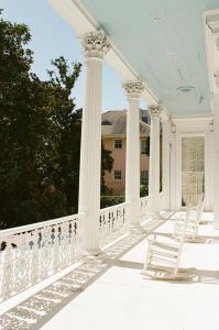 a row of white chairs sitting on top of a patio at The Magnolia Mansion in New Orleans