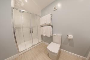 a white bathroom with a shower and a toilet at Silverstone Golf Club And Hotel in Silverstone +100 photos