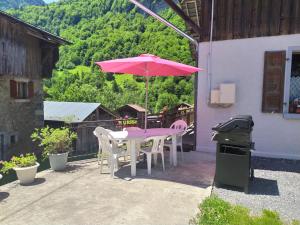 una mesa y sillas con una sombrilla rosa en el patio en La Ferme De Fernand, en Sixt
