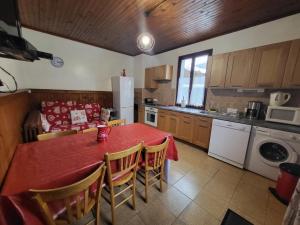 a kitchen with a red table and chairs and a kitchen with a refrigerator at La Ferme De Fernand in Sixt