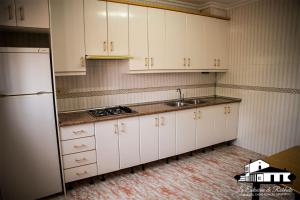 a kitchen with white cabinets and a sink and a refrigerator at Casas rurales la estación de Robledo in Robledo