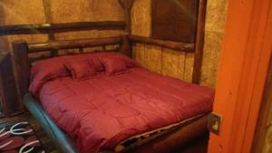 małe łóżko w pokoju z drewnianą ścianą w obiekcie Hostal ComplejoTurístico Santa Isabel w mieście Iza