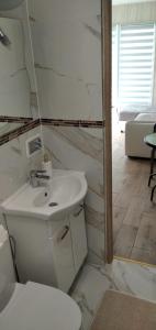 a white bathroom with a toilet and a sink at Domki u Anny in Gudowo