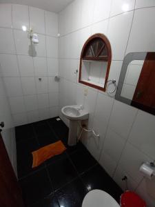uma casa de banho com um lavatório, um WC e um espelho. em Pousada casa nostra em Piúma