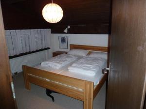 a bedroom with a bed with white sheets and a light at Ferienwohnung Murschetg in Laax