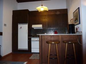 eine Küche mit einer Bar mit Hockern und einem Kühlschrank in der Unterkunft Ferienwohnung Murschetg in Laax