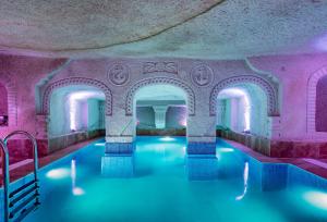 a swimming pool with pink walls and blue water at Cappadocia Ennar Cave Swimming Pool Hot & SPA in Nevsehir