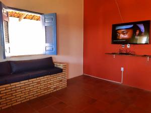 sala de estar con sofá y TV en la pared en Casa em Águas Belas CE, en Águas Belas