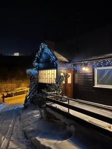 dom z lampkami świątecznymi na śniegu w obiekcie Domek nad Potokiem w mieście Słotwiny