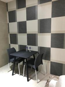 a black table and chairs in a room with a checkered wall at Terracota Corner Rooms in Campeche