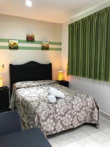 1 dormitorio con cama y cortinas verdes en Terracota Corner Rooms en Campeche