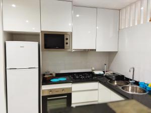 a kitchen with white cabinets and a white refrigerator at Apto Morabeza T2 Praia in Praia