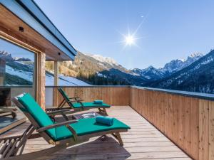 a deck with chairs and a view of the mountains at Berg'k'hof Kaisertal - Alpine Hideaway in Ebbs