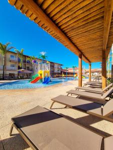 uma piscina com espreguiçadeiras e um parque infantil em Ondas Praia Resort em Porto Seguro