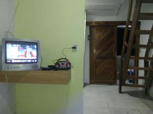 een kleine televisie op een plank naast een deur bij cantinho bom in Ubatuba