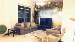 uma sala de estar com um sofá e uma televisão de ecrã plano em أزهار الكرز "سويت ملكي مطل على البحر" em King Abdullah Economic City