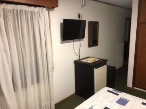 a bedroom with a bed and a television on the wall at Wiener Haus Hotel in Piriápolis