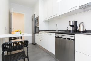 a kitchen with white cabinets and a chair in it at Stay Barcelona Central Apartments in Barcelona