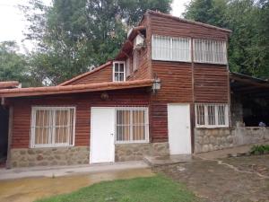 een houten huis met witte deuren en ramen bij Cabañas La Caballeriza San Lorenzo in Salta