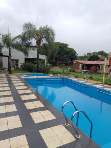 uma grande piscina com água azul e palmeiras em Cabañas La Caballeriza San Lorenzo em Salta