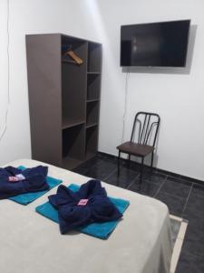 1 dormitorio con 2 albornoces azules en una cama con silla en Pillanhuasi alquiler por dia en Villa Unión