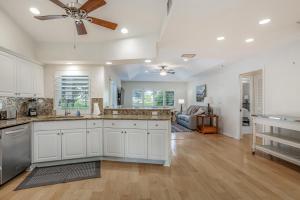 a kitchen with white cabinets and a ceiling fan at Golf-Course Oasis in Naples