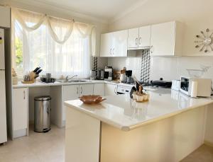 eine Küche mit weißen Schränken und einer weißen Arbeitsplatte in der Unterkunft Bright & Beautiful Home On The Hills! in Kelmscott
