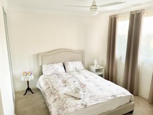 Bright & Beautiful Home On The Hills! في Kelmscott: غرفة نوم بيضاء عليها سرير وساعة